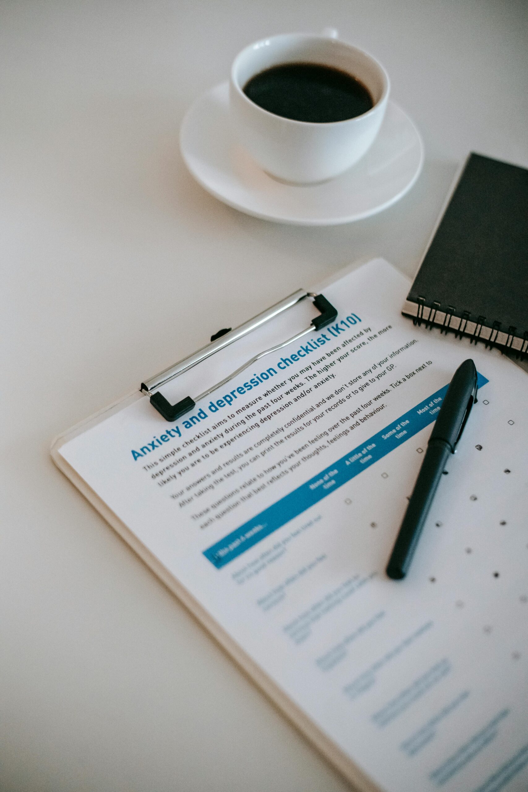 From above of cup of hot coffee on table with clipboard and notepad in office of psychologist